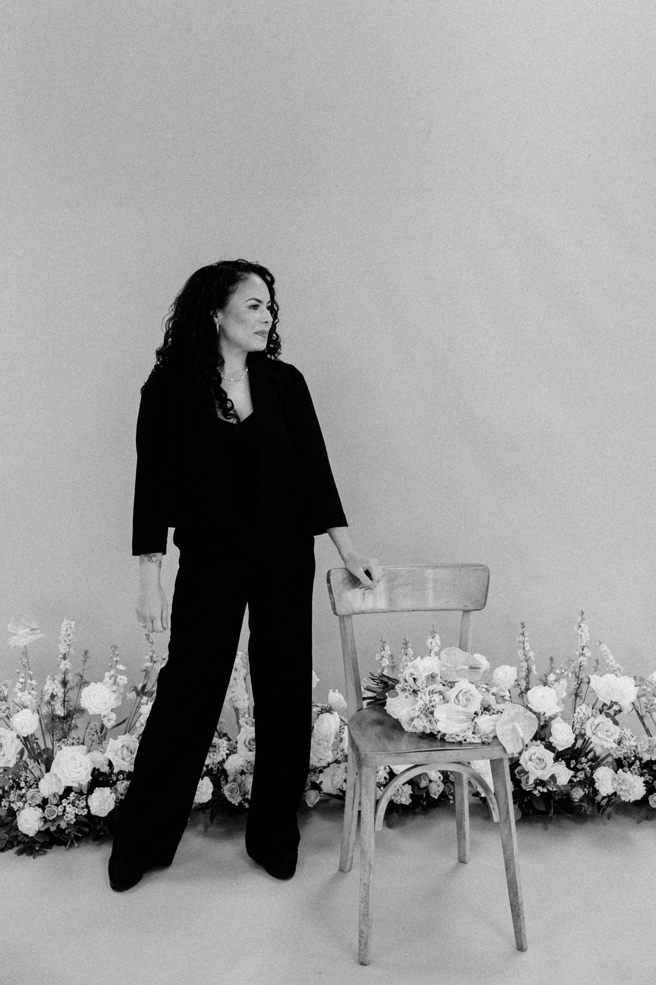 Founder of Oasis Weddings and Events in a black and white studio portrait with white florals