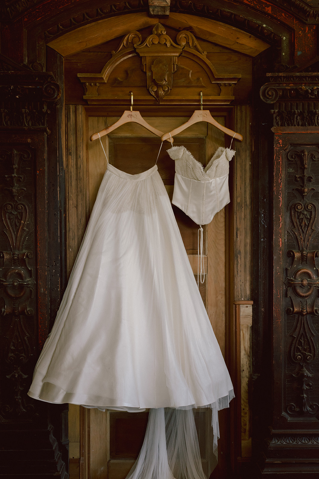 Bridal gown and corset hanging in an antique carved doorway